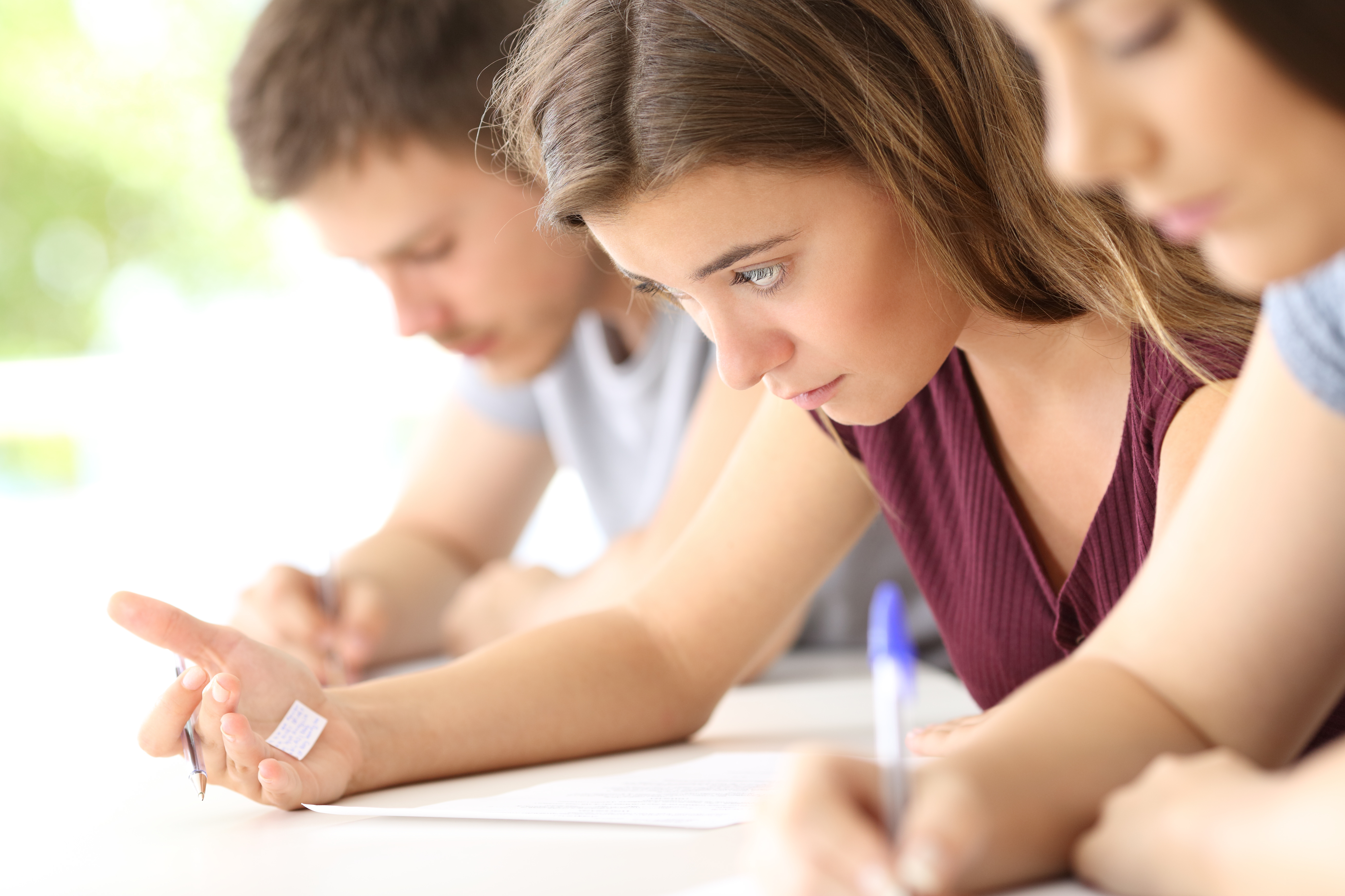 Bad student reading a cheating sheet during an exam in a classroom